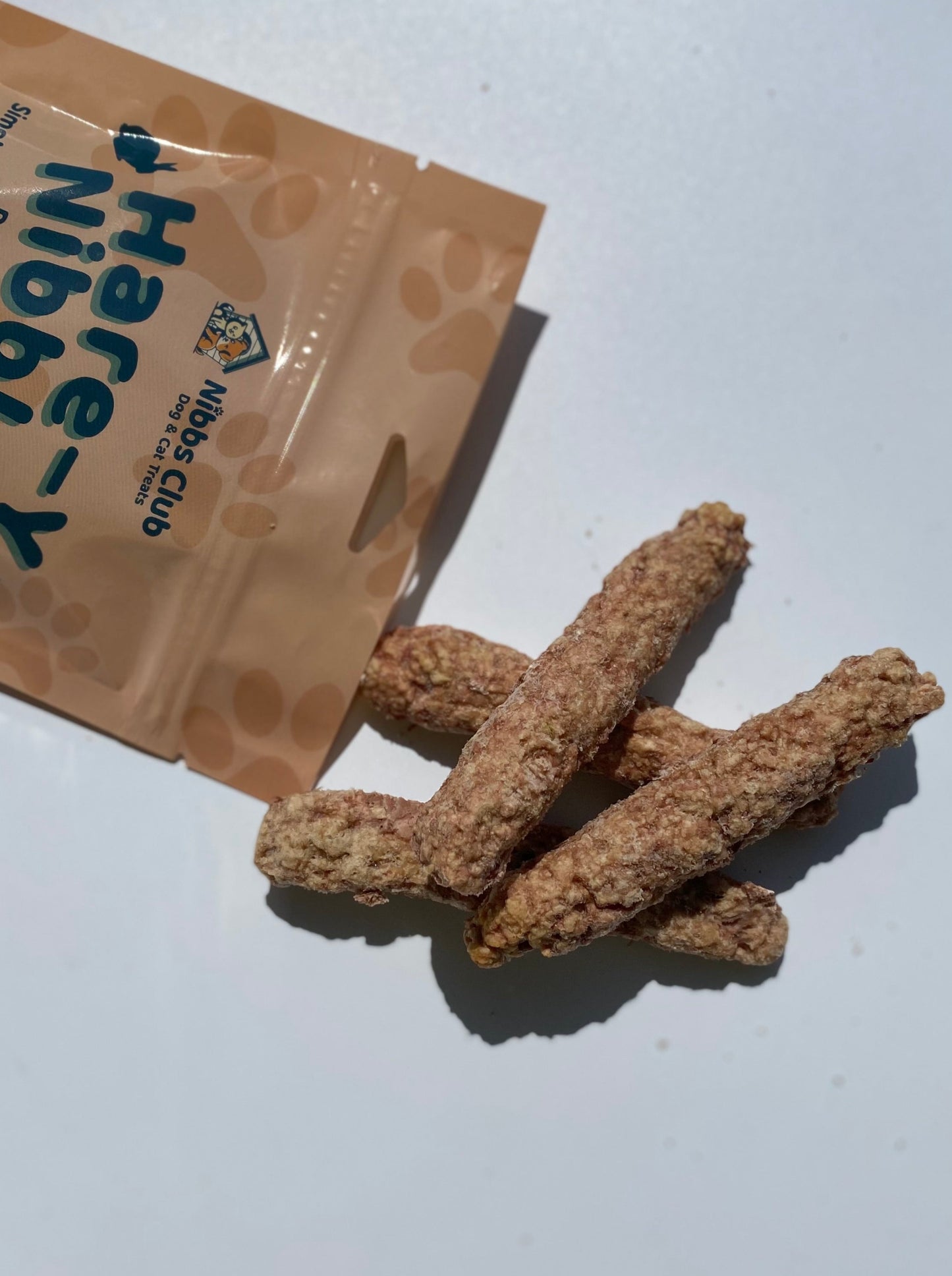 Hare-Y Nibble dog and cat treats being poured out of a bag on top of a white background